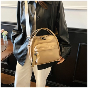 Side view of beige nylon crossbody bag worn by model in casual street style outfit