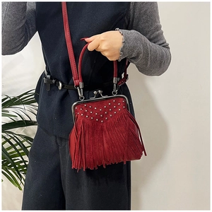 Dettaglio di una borsa a tracolla in pelle scamosciata rossa con nappe e borchie in metallo