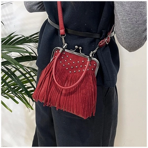 Detail of red suede crossbody bag with vintage tassels and silver stud decorations