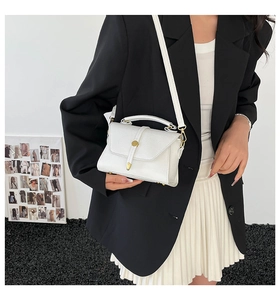 Detailed shot of white lychee leather handbag with gold metal clasp on a model