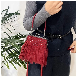 Close-up of red suede fringe crossbody bag with silver rivets and kiss-lock metal clasp