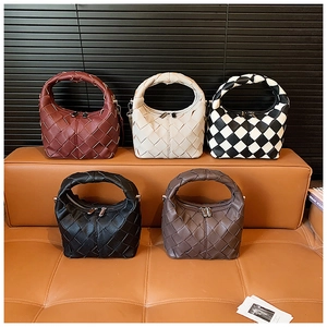 Collection of woven leather handbags in various colors arranged on a luxury bench