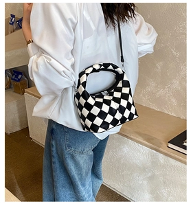Detail of black and white checkered crossbody bag featuring textured PU leather and silver zipper