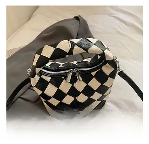 Detail of woven checkerboard leather bag with dual metal zippers and a slim shoulder strap