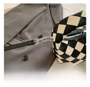 Detail of silver metal hook and pebble grain texture on checkered woven bag