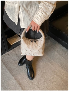 Beige woven crescent handbag styled with casual fashion outfit in a bright studio