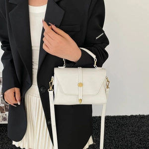 Minimalist white pebbled leather handbag with gold stud detail shown with model attire