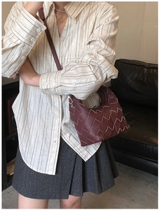 Close-up of burgundy woven leather handbag with contrast stitching and fine strap detail