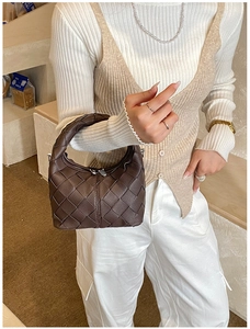 Close-up of dark brown woven leather handbag with intricate craftsmanship and zipper detail