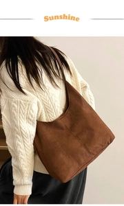 Detail of deep brown suede tote bag worn with a white knit sweater for autumn style