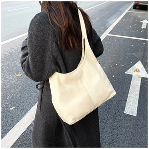 Outdoor street style shot of a cream soft leather tote bag with wide shoulder strap