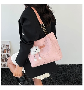 Detail of pink tote bag with silver star patterns, plush cloud charm and metal chain strap