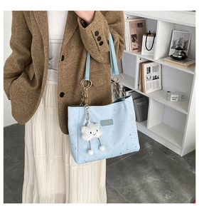 Detail of light blue tote bag featuring silver star patterns and cloud charm accessory