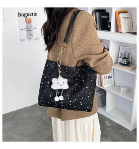 Detail of black tote bag with star pattern, chain strap and cloud plush pendant