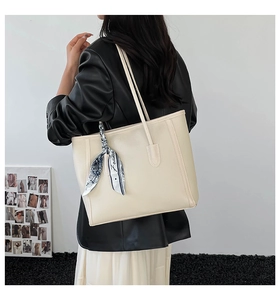 Detail of off-white tote bag with lychee texture and decorative silk scarf on the side