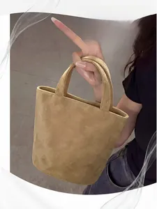 Detail view of khaki suede tote bag with dual handles held by a model in casual style