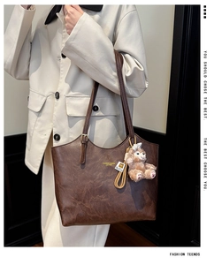 Detail of dark brown lychee texture tote bag with a cute plush bear charm accessory