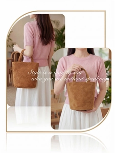Detail of a large capacity brown suede bucket bag featuring elegant texture and minimalist handle
