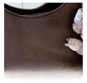 Close-up of brown litchi pattern leather tote with gold-stamped letters and plush charm