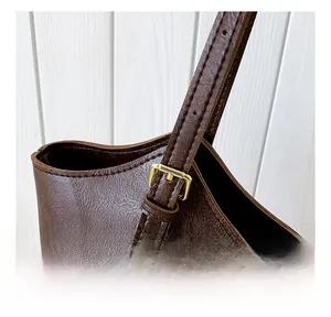 Close-up of brown litchi pattern leather tote bag showing gold metal buckles and stitching