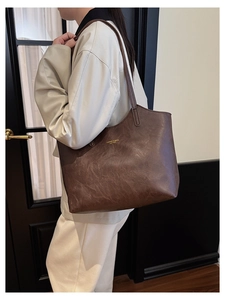Detailed shoulder view of a brown vintage tote bag with gold-printed leather text