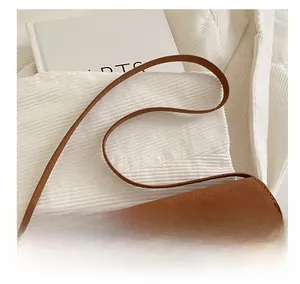 Close-up of brown suede shoulder bag with gold metal buckle on white books