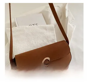 Detailed close-up of brown suede shoulder bag with gold-tone horseshoe buckle hardware