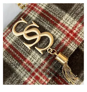 Macro shot of brown tweed texture with golden tassel and metal buckle on the crossbody bag