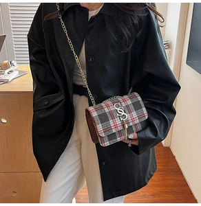 Detail of red and grey plaid crossbody bag with gold chain and metal tassel ring clasp