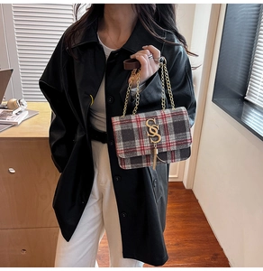 Detail of plaid crossbody bag with gold letter S charm and metallic tassel accessory