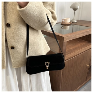 Detailed view of a black matte baguette bag featuring a gold horseshoe clasp and shoulder strap