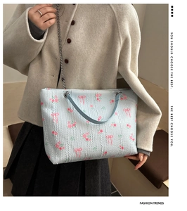 Detail of light blue quilted tote bag featuring floral print and metal chain strap