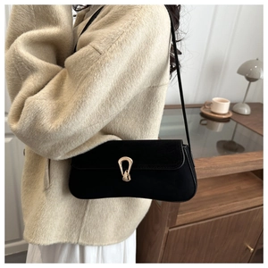 Close-up of black suede underarm bag with elegant gold U-shaped buckle detail