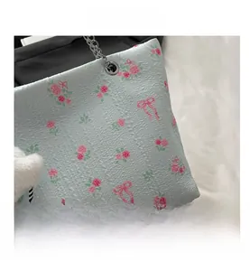 Detail of light blue rose and bow print tote bag with silver chain strap and plush charm
