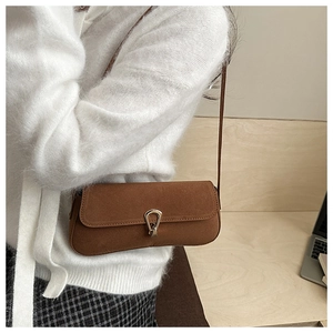 Detail view of brown suede baguette bag featuring a gold U-shaped metal buckle clasp