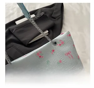 Detailed close-up of light blue corduroy tote bag with pink rose and bow floral patterns