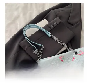 Detail of light blue floral bucket bag with chain strap and plush cloud charm