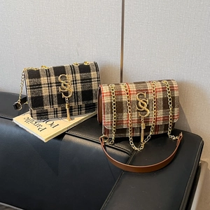 Retro plaid wool shoulder bag with gold metal tassel logo on a stylish leather sofa