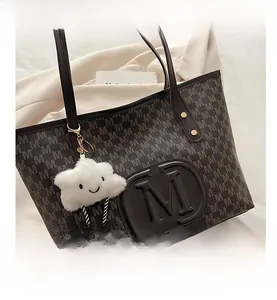 Detail of dark brown tote bag with M-letter jacquard and cute plush cloud charm