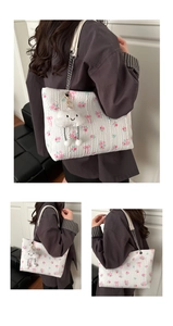 Detail of white floral bucket bag with chain strap and cute plush cloud pendant charm