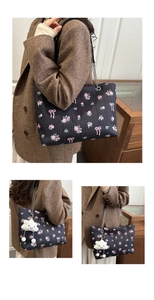 Close-up of black bucket bag with pink floral rose print and plush cloud charm