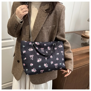 Detail of floral tote bag with rose patterns, metal chain strap, and pleated fabric texture