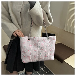 Detail of pink floral bucket bag with bow patterns and silver chain shoulder strap