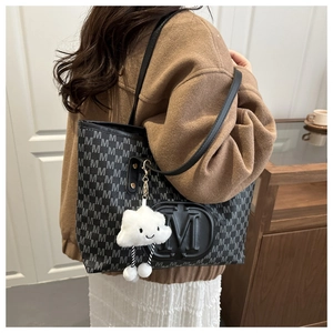 Détail d'un sac cabas noir avec motif M et pendentif nuage en peluche pour femmes