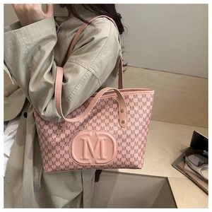 Close-up of pink tote bag with M letter monogram and embossed logo on beige trench coat