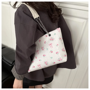 Close-up of floral shoulder bag with pink roses and silver chain strap on model