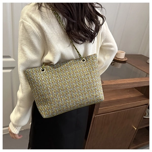 Detail of multi-color woven tote bag with metal leather chain strap on a model