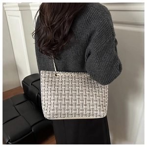 Detail view of woven check tote bag with gold chain strap worn by a model