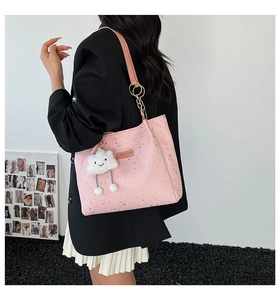 Pink star-print tote bag with white cloud plush pendant worn by model in black suit