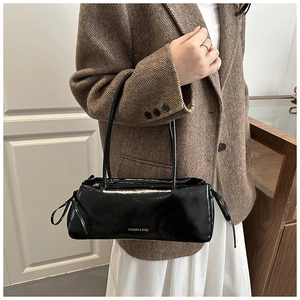 Detail of glossy black patent leather shoulder bag with white fashion text and side drawstring